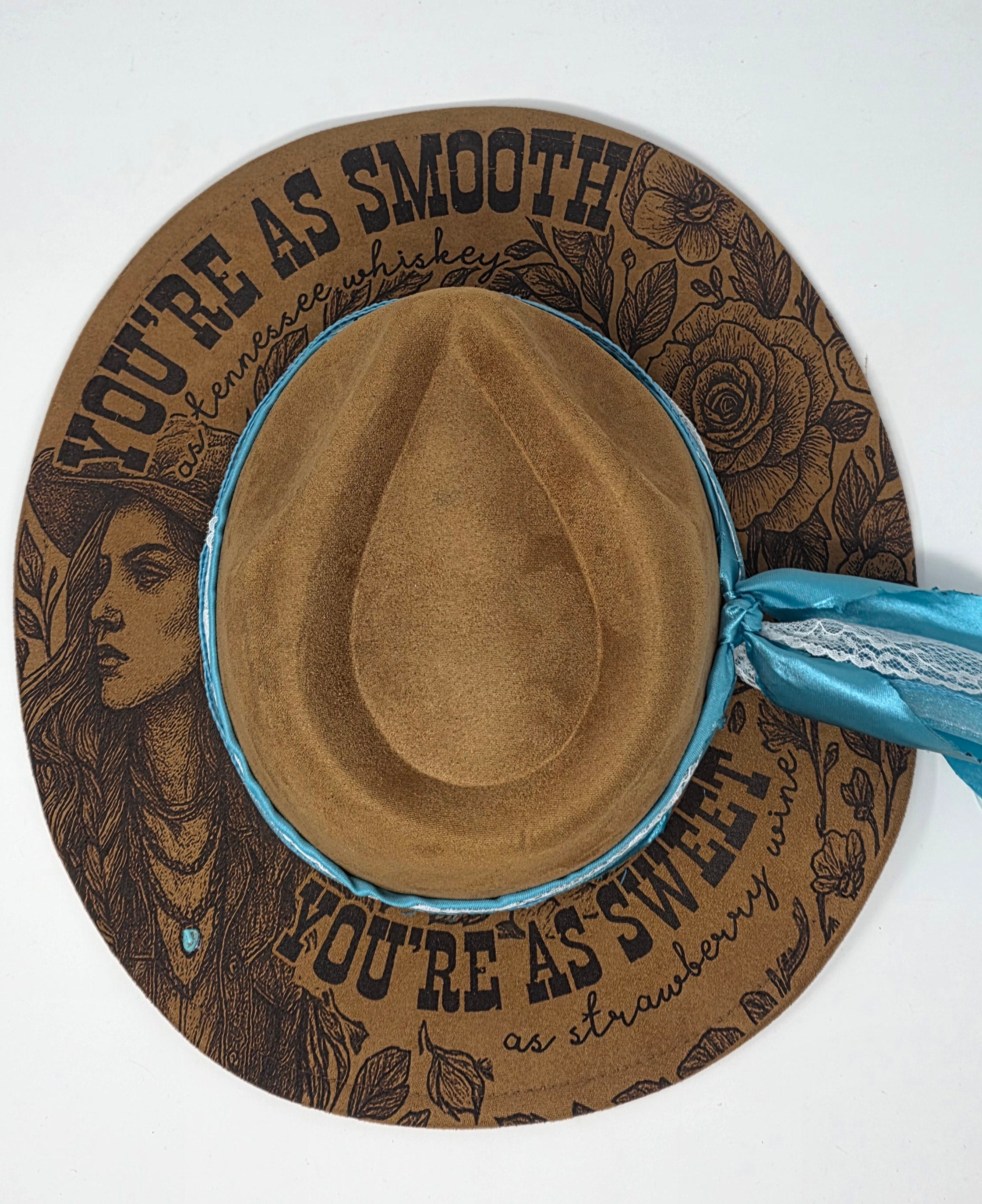 Brown cowboy hat with decorative band featuring text and illustrations on a white background