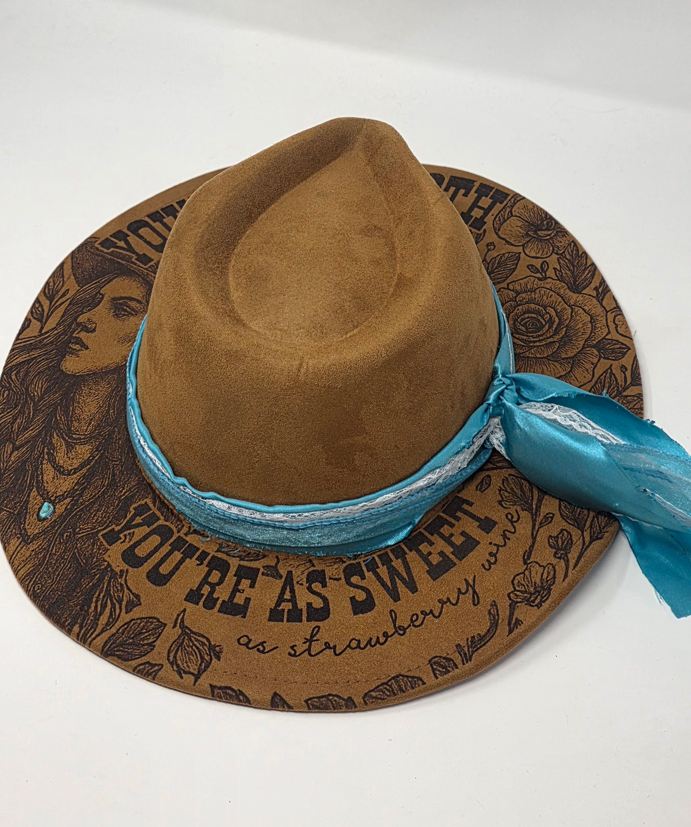 Brown cowboy hat with blue band on a decorative mat with text and graphics