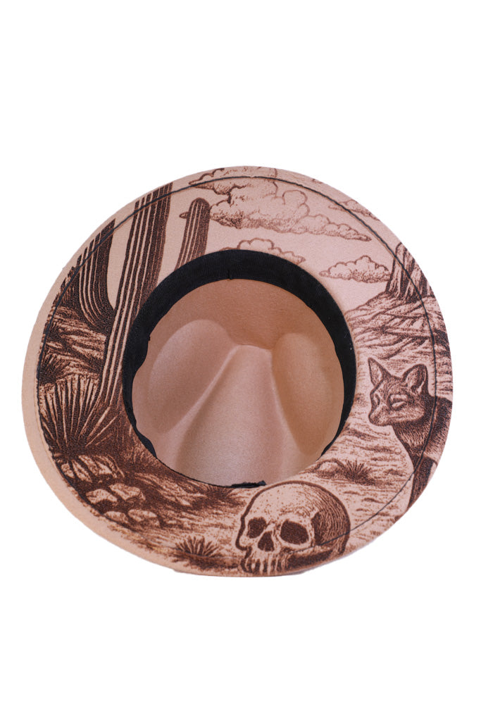 Underside brim engraving showing skull, cactus, and desert landscape