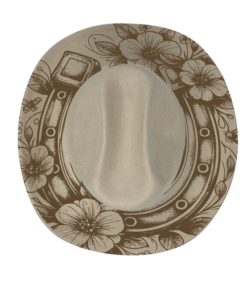 A biege cattleman hat with a horseshoe and floral pattern engraving on the brim