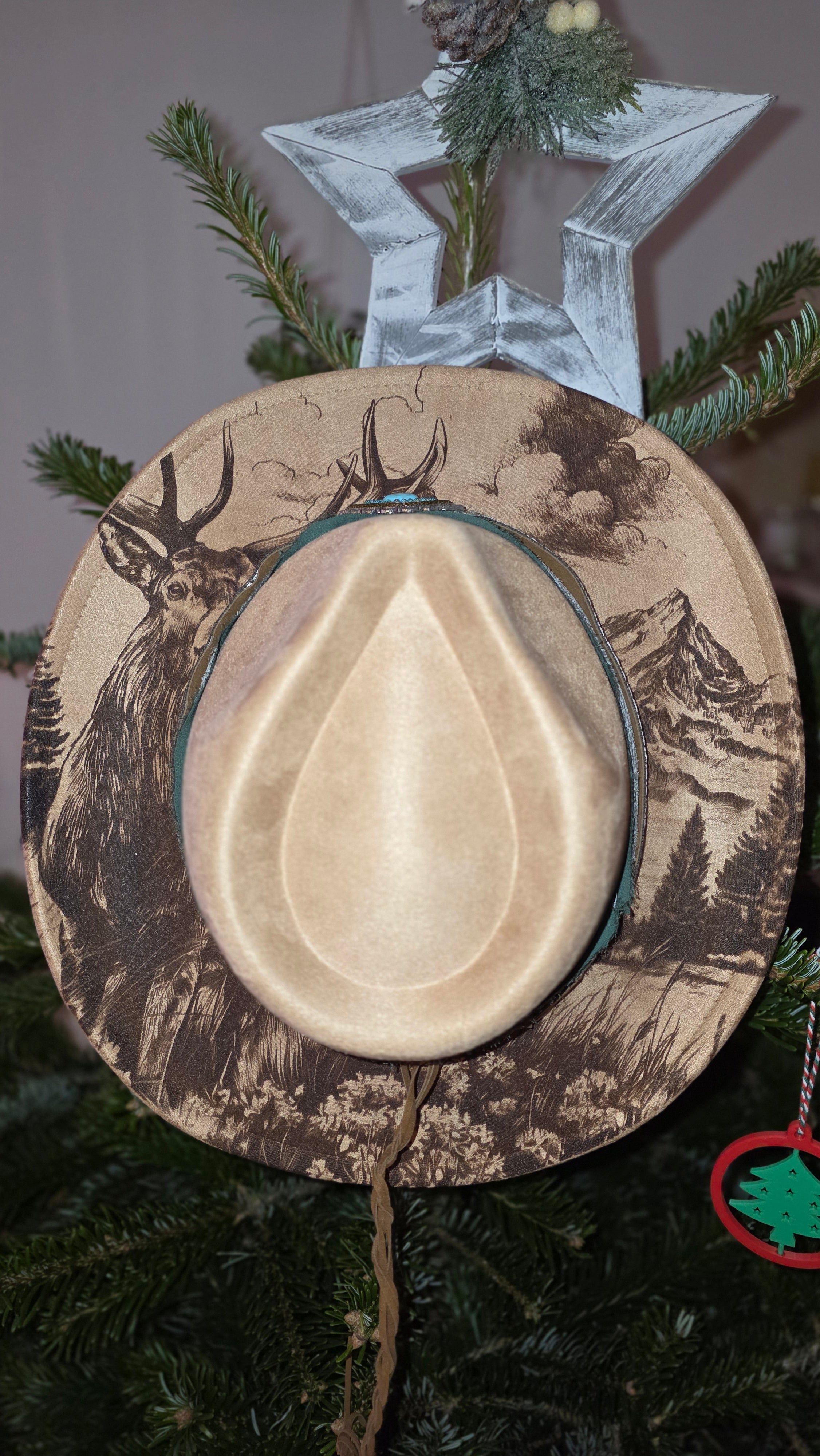Laser engraved fedora hat with woodland stag and mountain design on brim.